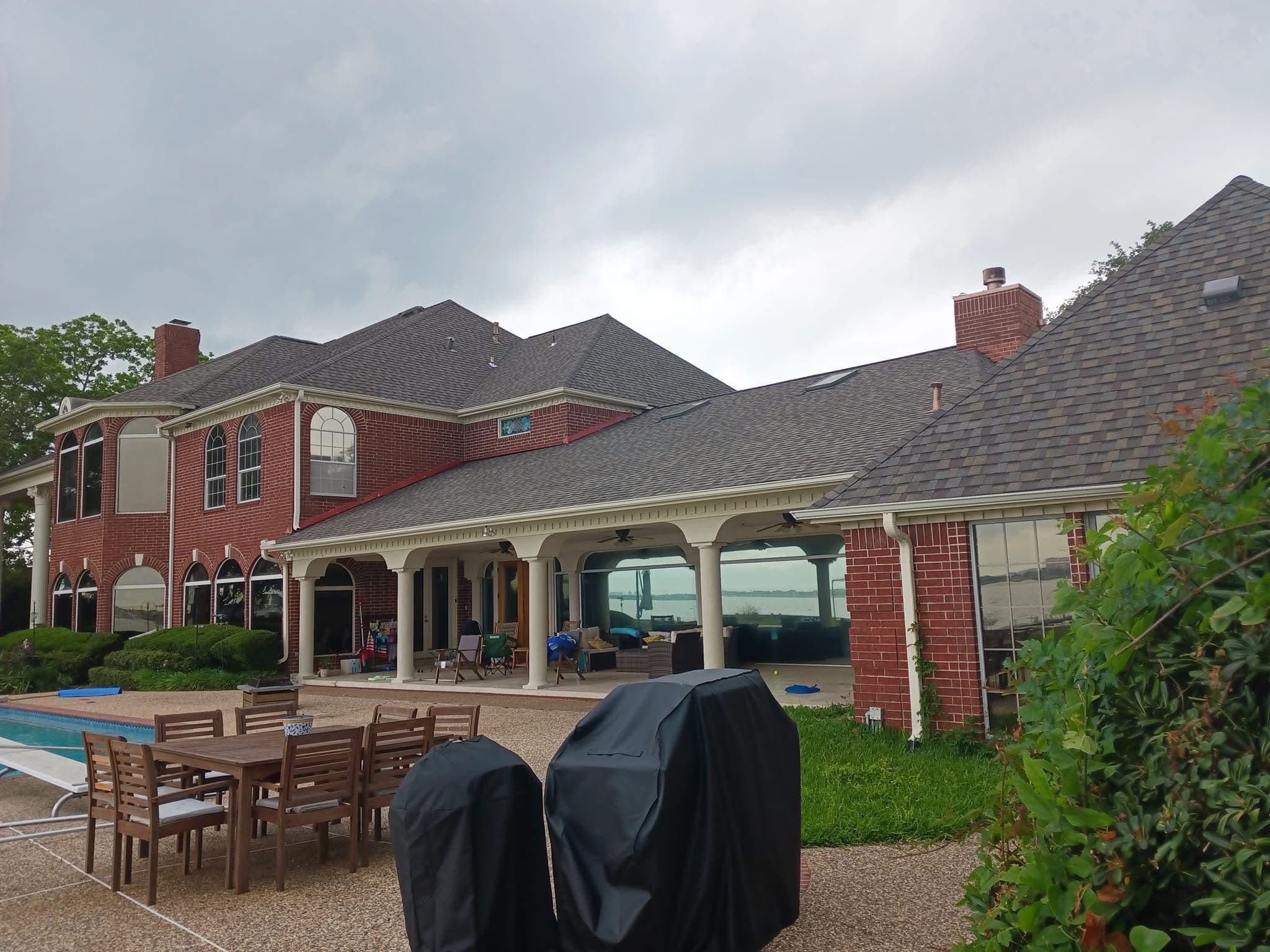 Large brick waterfront home with a newly installed architectural shingle roof